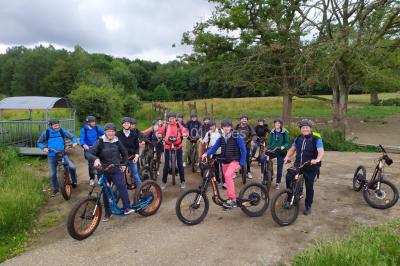 Dépliant sur des trottinettes électriques tout terrain posé sur une table avec viennoiseries et jus d'orange en arrière-plan.