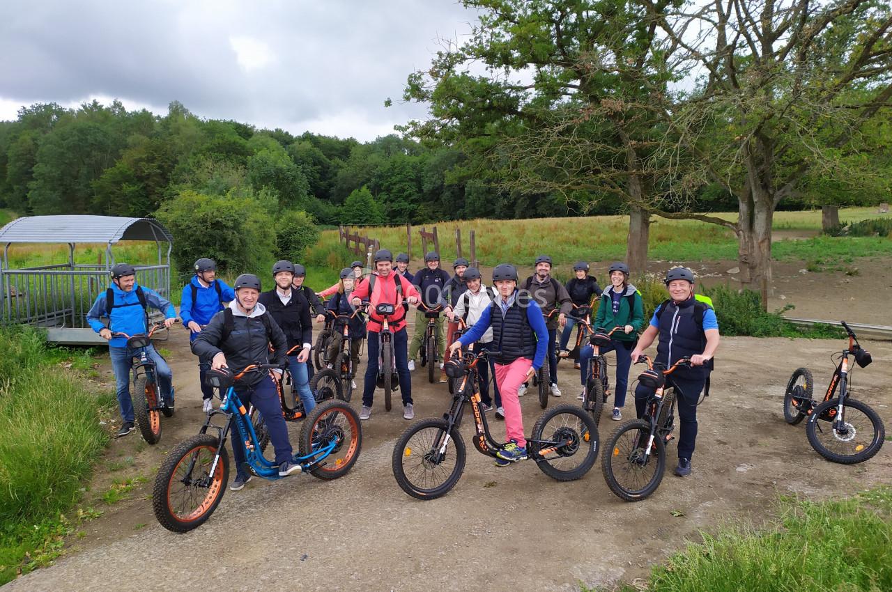 Un groupe de personnes en trottinettes tout-terrain posant sur un chemin en pleine nature.