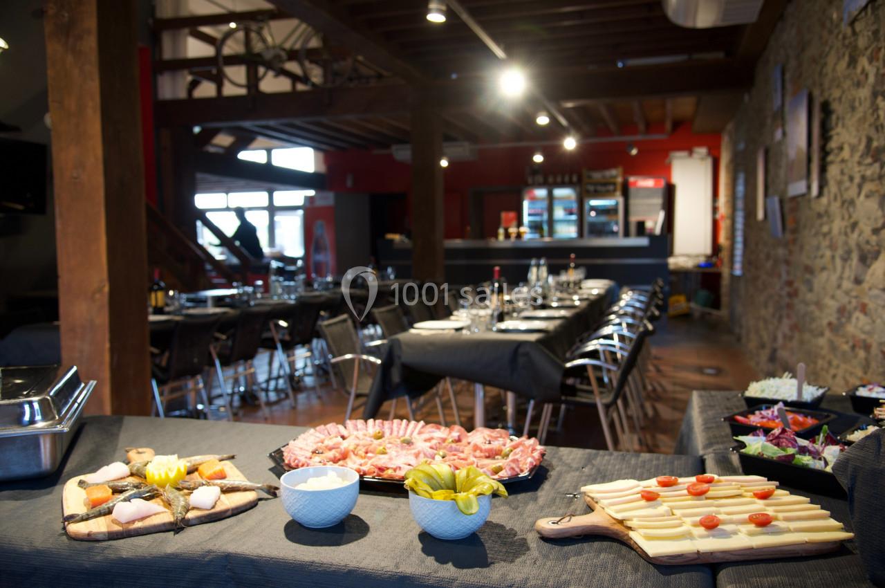 Buffet avec charcuterie, fromage, légumes et salades, dans une salle de réception au décor rustique.