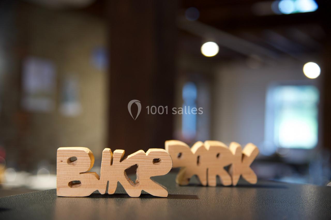 Sculptures en bois formant les mots ’Bike Park’ posées sur une surface sombre dans un intérieur flou.