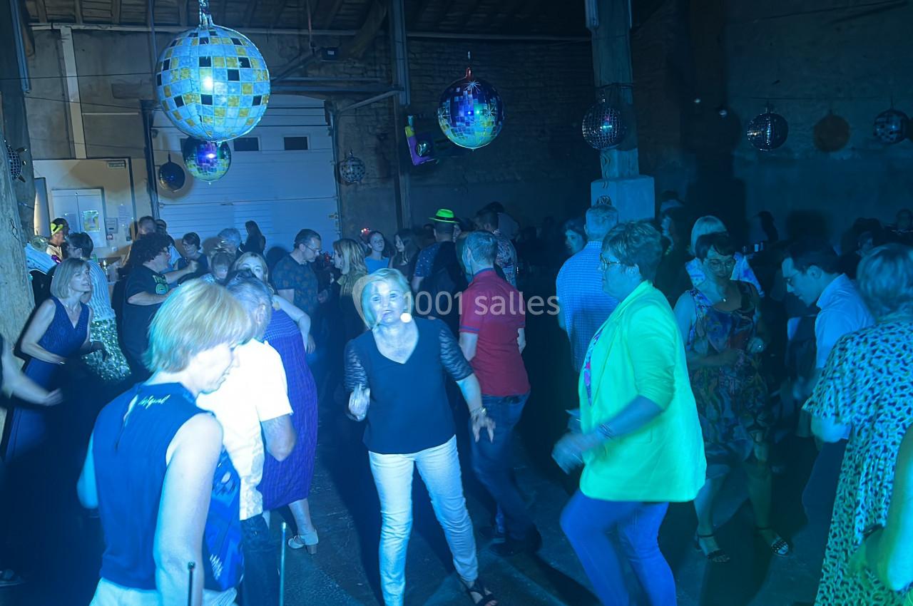 Des personnes dansent dans une salle éclairée par des lumières colorées et des boules à facettes.