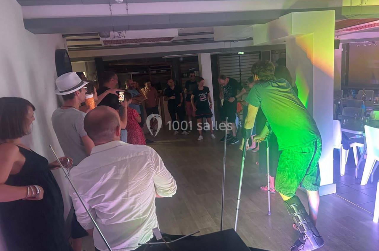 Des personnes assistent à un événement dans une salle éclairée, un homme en béquilles au premier plan.