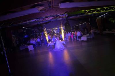 Des personnes dansent dans une salle éclairée par des lumières rouges, entourées de tables dressées pour un événement.