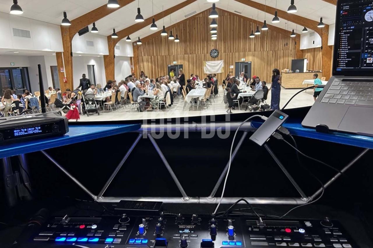 Vue depuis une table de mixage sur une salle de réception animée, avec des invités assis à des tables.