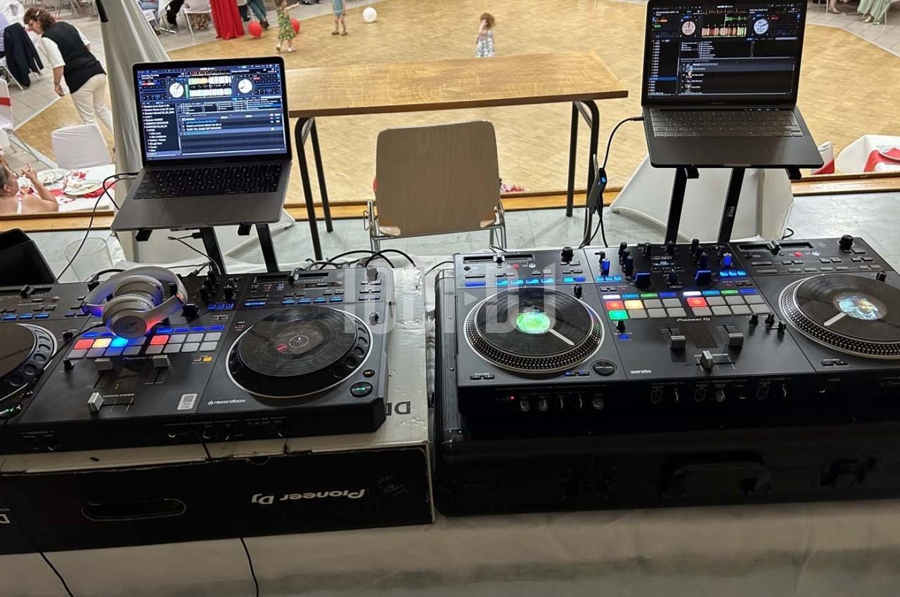 Poste de DJ avec deux platines, une table de mixage et deux ordinateurs portables dans une salle de réception.