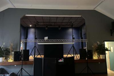 Des personnes dansent dans une salle éclairée par des lumières rouges, entourées de tables dressées pour un événement.