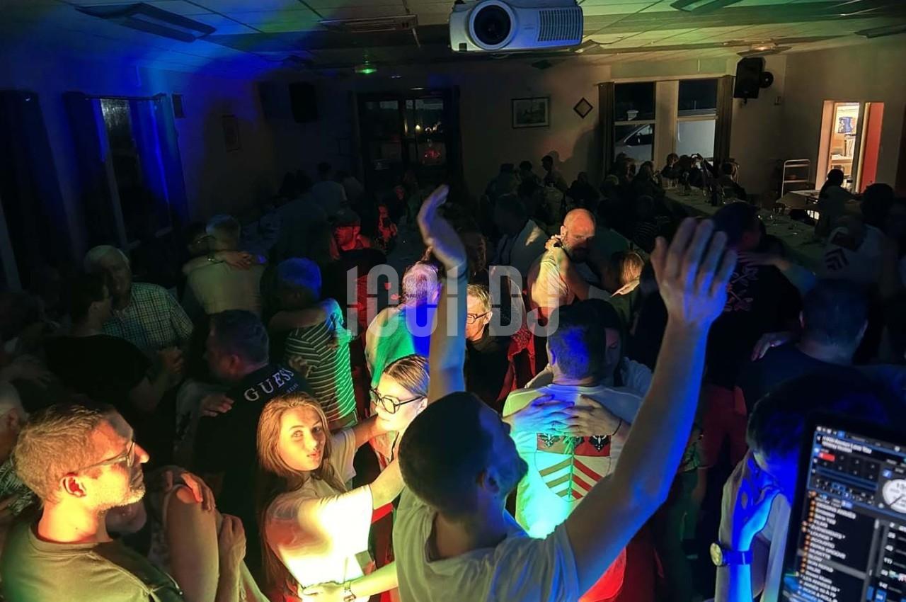 Groupe de personnes dansant et socialisant dans une salle éclairée par des lumières colorées.