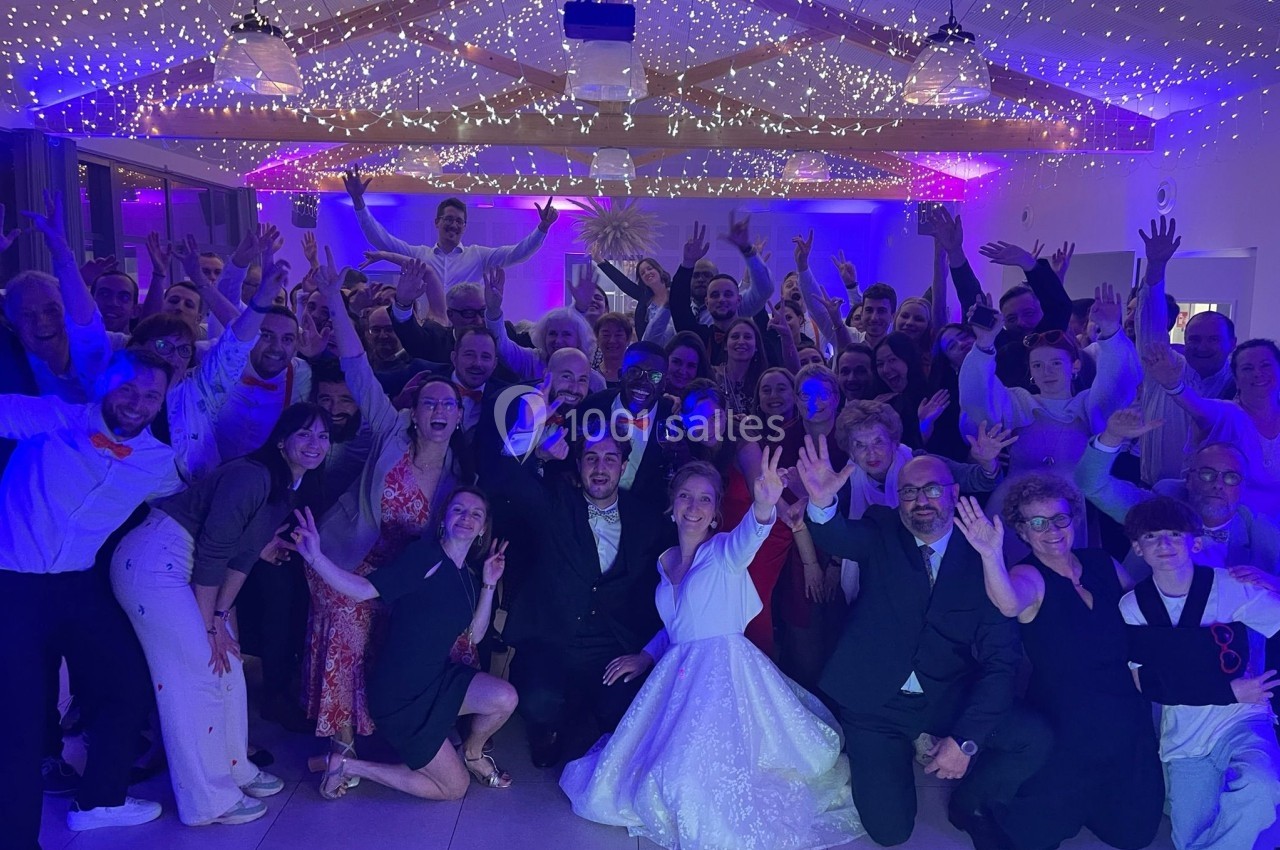 Un grand groupe de personnes pose joyeusement dans une salle illuminée de guirlandes et de lumières colorées.