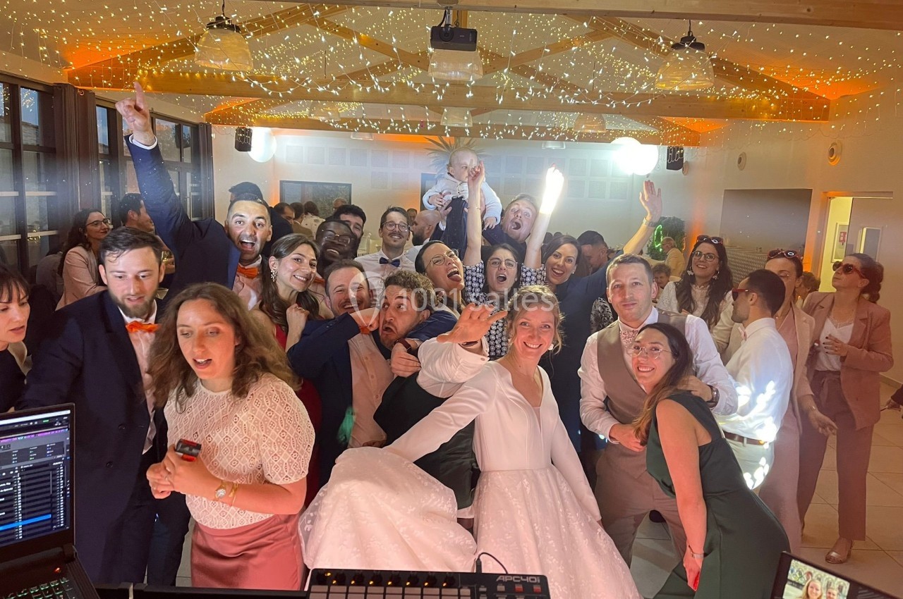 Un groupe de personnes souriantes posant joyeusement dans une salle décorée de guirlandes lumineuses.