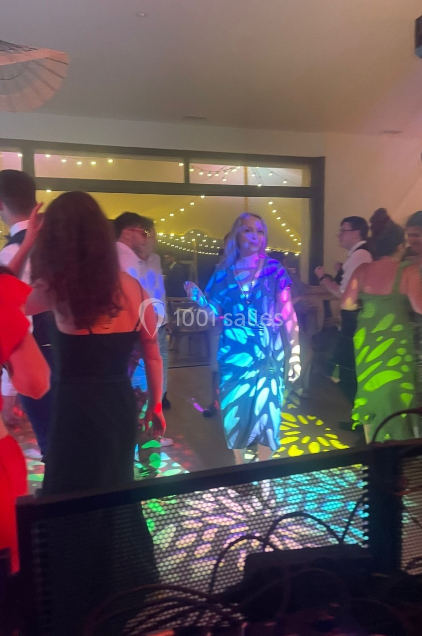 Des personnes dansent dans une salle éclairée par des lumières colorées, créant des motifs au sol et sur les murs.