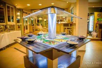 Buffet lumineux avec compartiments remplis de salades et condiments, entouré de bols dans une salle de restaurant.