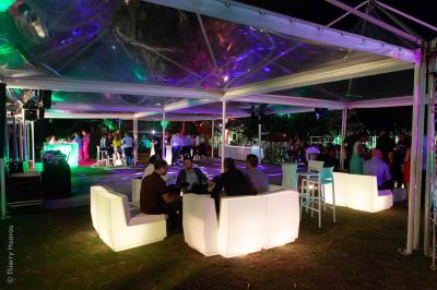 Groupe de personnes rassemblées dans un jardin éclairé par des guirlandes lumineuses lors d'un événement nocturne.