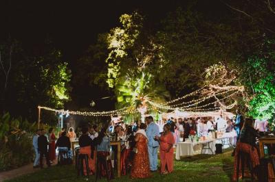 Groupe de personnes rassemblées dans un jardin éclairé par des guirlandes lumineuses lors d'un événement nocturne.