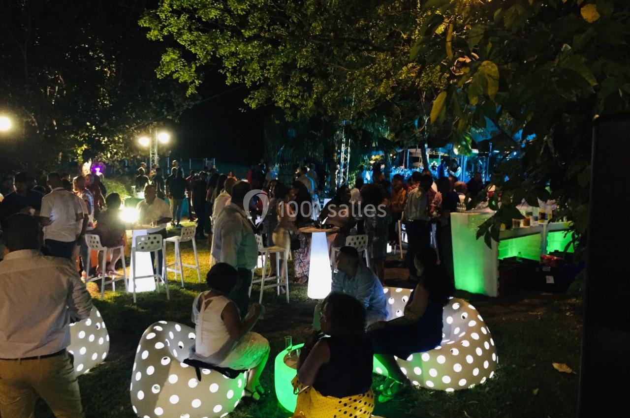 Groupe de personnes réunies en soirée en plein air, éclairées par des lumières colorées et des sièges lumineux.