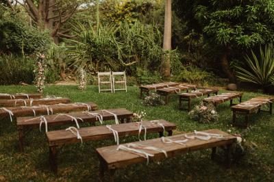 Bancs en bois disposés sur une pelouse pour une cérémonie en plein air, entourés de végétation et de fleurs.