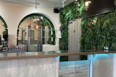 Comptoir moderne devant un mur végétal intérieur avec arches, éclairage discret et équipements de restauration.