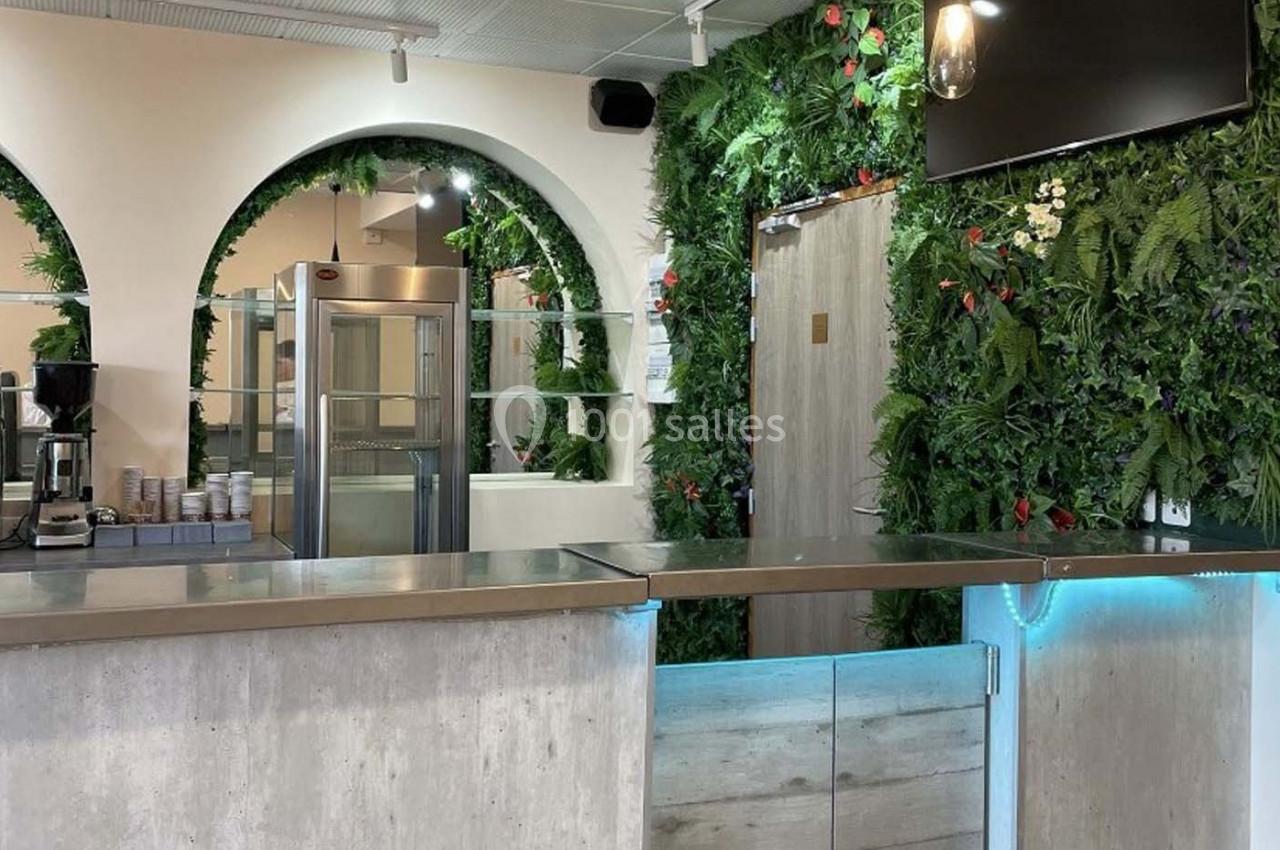 Comptoir moderne dans un espace lumineux avec murs ornés de plantes vertes et arches décoratives.