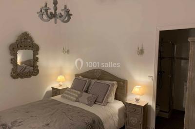 Chambre avec un lit double, éclairage doux et une grande bibliothèque en bois remplie de livres en arrière-plan.