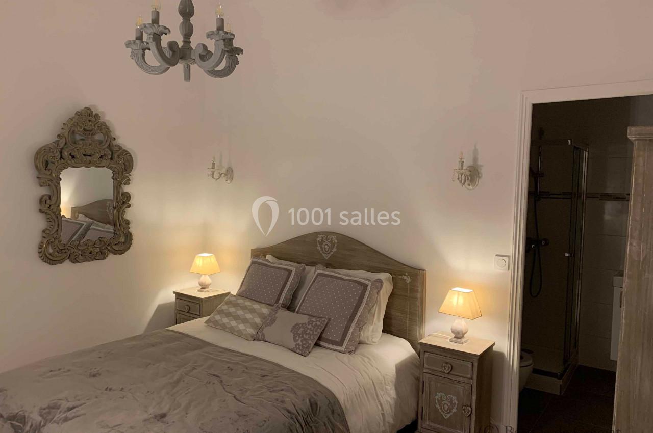 Chambre décorée de manière classique avec un lit double, des lampes de chevet allumées et un miroir mural orné.