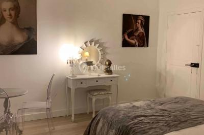 Chambre avec un lit double, éclairage doux et une grande bibliothèque en bois remplie de livres en arrière-plan.