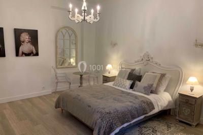 Chambre avec un lit double, éclairage doux et une grande bibliothèque en bois remplie de livres en arrière-plan.