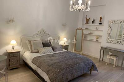 Chambre avec un lit double, éclairage doux et une grande bibliothèque en bois remplie de livres en arrière-plan.