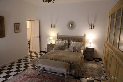 Chambre avec un lit double, éclairage doux et une grande bibliothèque en bois remplie de livres en arrière-plan.