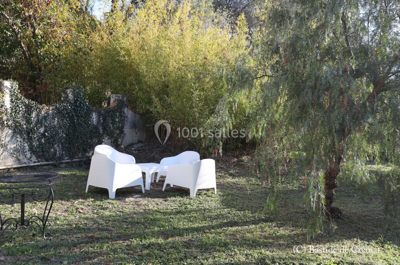 Mobilier de jardin blanc disposé sur une pelouse, entouré de végétation et d'arbres.