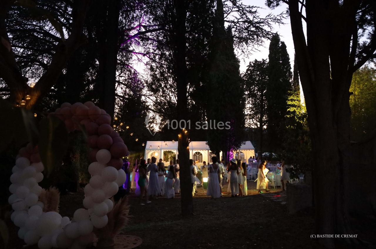 Groupe de personnes rassemblées en soirée dans un jardin éclairé, avec des décorations lumineuses et une arche de ballons.