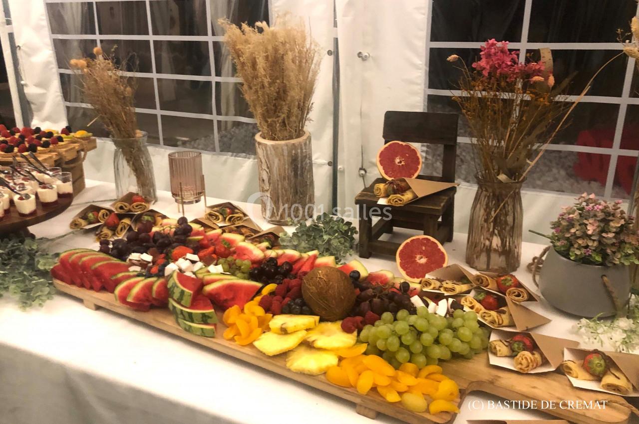 Plateau de fruits frais variés avec des pâtisseries, disposé sur une table décorée de plantes et de fleurs séchées.