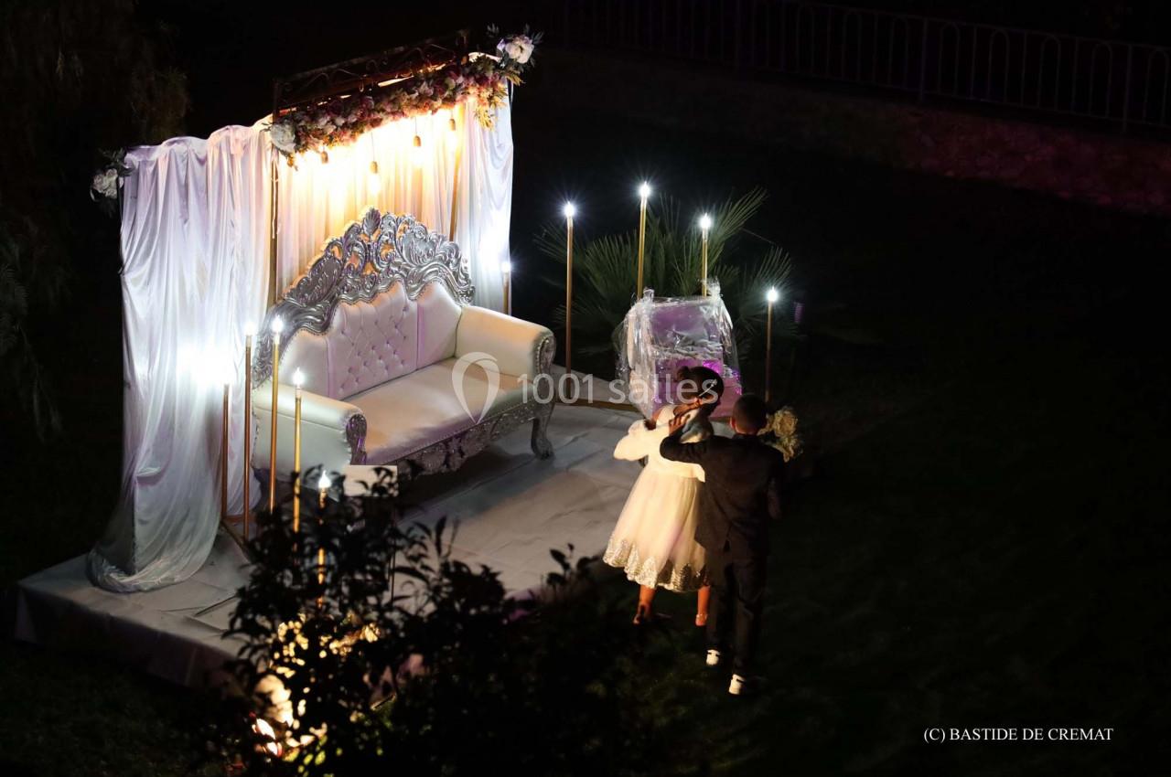 Un couple danse devant un canapé décoré et illuminé dans un cadre extérieur nocturne.