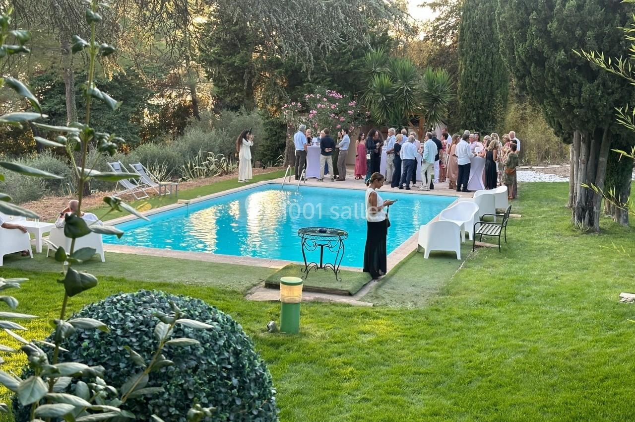 Groupe de personnes rassemblées près d'une piscine dans un jardin entouré d'arbres et de verdure.