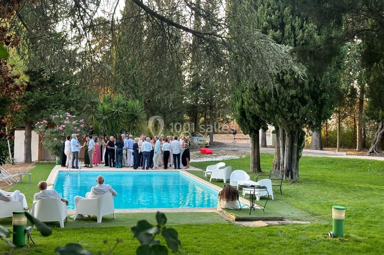 Groupe de personnes rassemblées près d'une piscine dans un jardin entouré d'arbres.