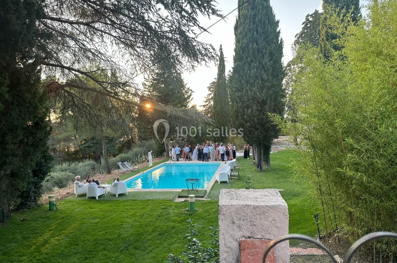 Groupe de personnes réunies près d'une piscine entourée de verdure et d'arbres au coucher du soleil.