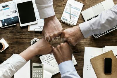 Ours en peluche avec un nœud rose devant un présentoir de cupcakes décorés dans un décor rose et lumineux.