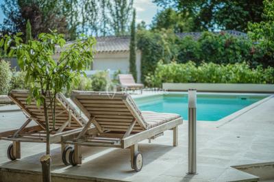 Un couple de mariés lève les bras en l'air devant des invités lors d'une réception en extérieur près d'une piscine.