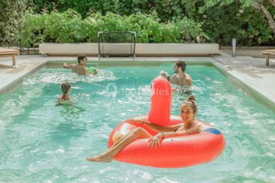 Un couple de mariés lève les bras en l'air devant des invités lors d'une réception en extérieur près d'une piscine.