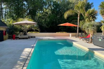 Un couple de mariés lève les bras en l'air devant des invités lors d'une réception en extérieur près d'une piscine.