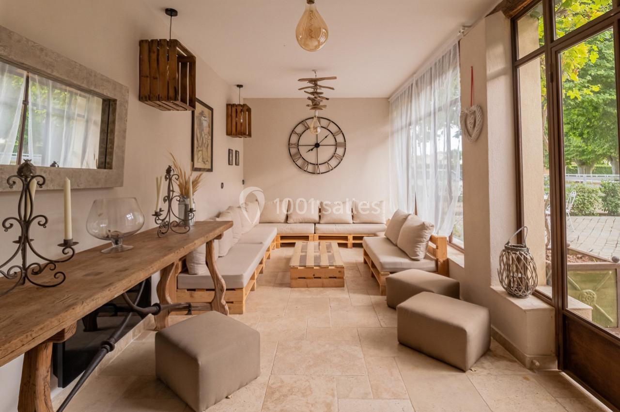 Salon lumineux avec canapé d'angle en bois clair, table basse assortie, grande horloge murale et vue sur jardin.