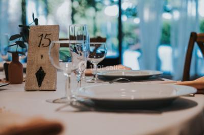 Table décorée avec des bougies allumées, des fleurs séchées et fraîches dans des vases, sur fond de rideaux blancs.