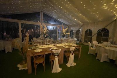 Table décorée avec des bougies allumées, des fleurs séchées et fraîches dans des vases, sur fond de rideaux blancs.