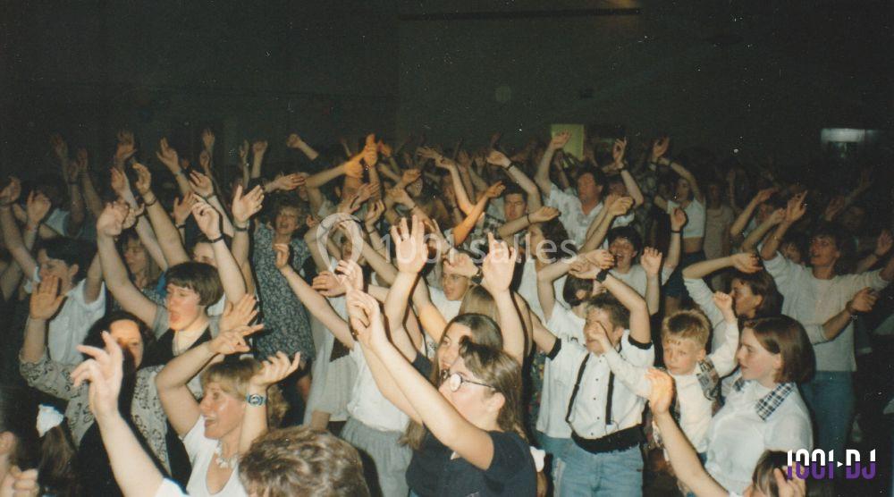 Foule de personnes levant les bras lors d'un événement festif dans une salle sombre.