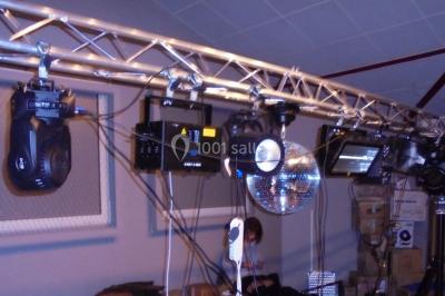 Salle sombre avec des poutres en bois, éclairée par des lumières colorées, des personnes discutent et se déplacent.