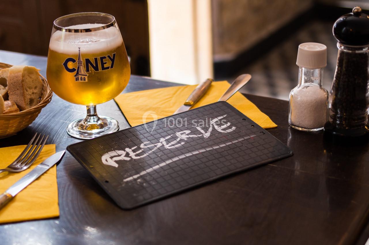 Verre de bière, panier de pain et ardoise marquée ’Réservé’ sur une table de restaurant.