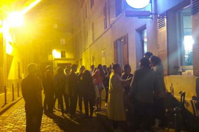 Bouteilles variées alignées sur une étagère en bois dans un bar avec une enseigne ’L'Astrolabe’ en arrière-plan.