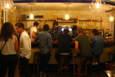 Bouteilles variées alignées sur une étagère en bois dans un bar avec une enseigne ’L'Astrolabe’ en arrière-plan.