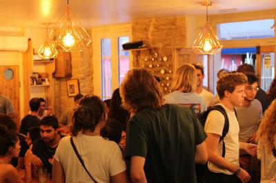 Bouteilles variées alignées sur une étagère en bois dans un bar avec une enseigne ’L'Astrolabe’ en arrière-plan.