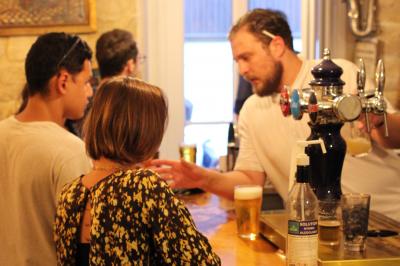 Bouteilles variées alignées sur une étagère en bois dans un bar avec une enseigne ’L'Astrolabe’ en arrière-plan.