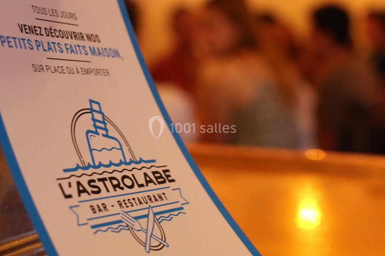 Affiche d'un restaurant nommé ’L'Astrolabe’ avec une offre de plats faits maison, floue en arrière-plan.