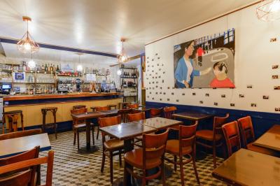 Bouteilles variées alignées sur une étagère en bois dans un bar avec une enseigne ’L'Astrolabe’ en arrière-plan.
